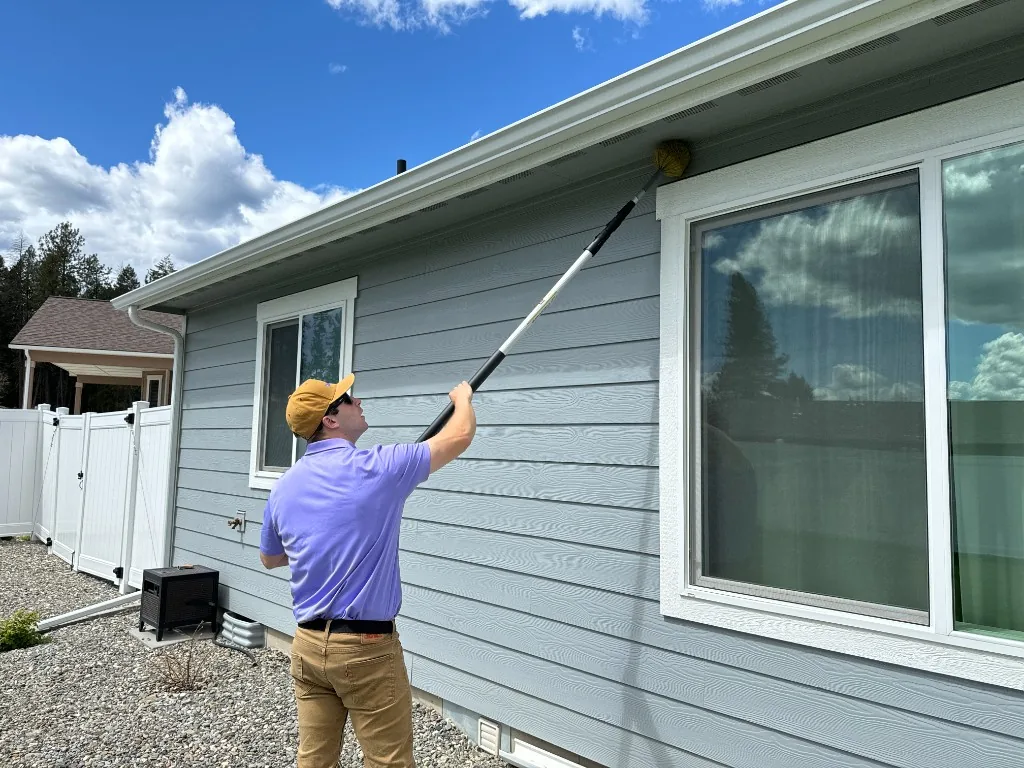 Spud Pest technician treating the eaves of a home with an extension pole
