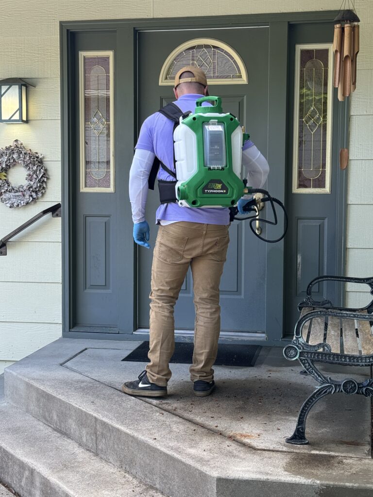 photo of spud pest control technician treating around the door of a home to prevent pest problems