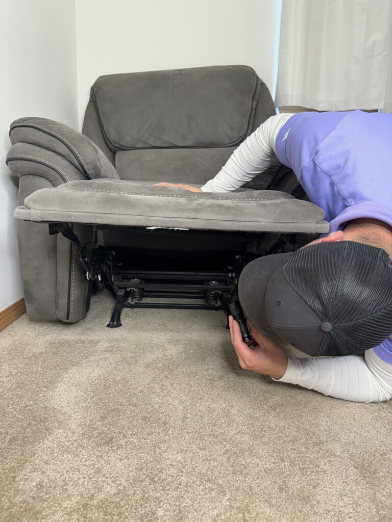 Bed Bugs a guy using a flashlight and checking under a chair for signs of bed bugs